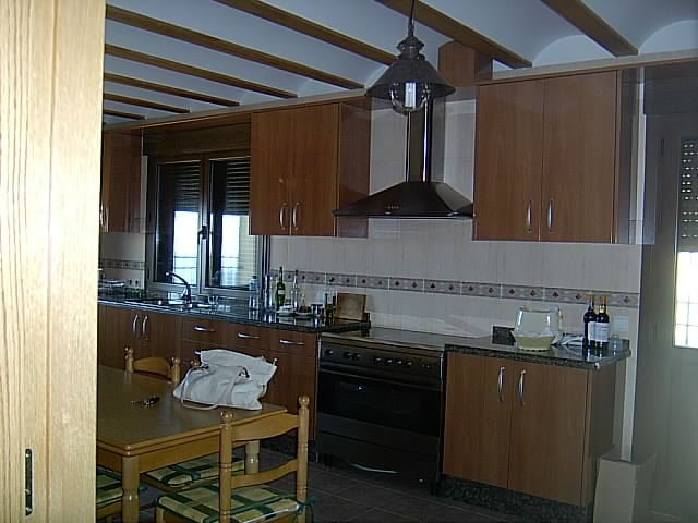 Charming kitchen in a finca located in Huescar, Granada, featuring wooden cabinets, modern appliance.
