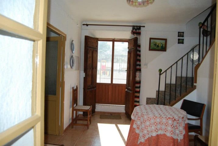 Cozy village home interior with wooden window shutters, staircase, and simple furnishings in Cuevas.