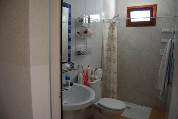 Small village bathroom with shower, sink, and window in Cuevas del Campo, Granada.