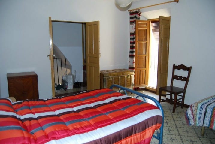 Cozy bedroom in a traditional village house in Cuevas del Campo, Granada, featuring wooden shutters.