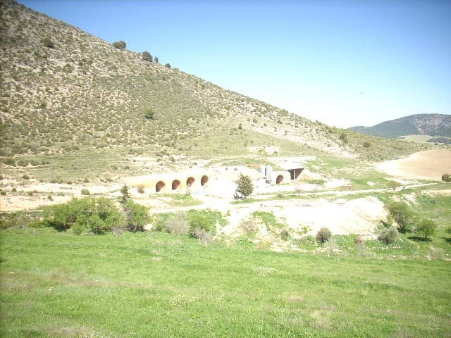 Finca with historic tunnels in Huescar, Granada, surrounded by lush green fields and rolling hills.