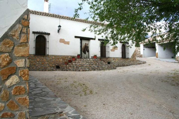 Finca in Huescar with traditional white walls and stone accents, set in scenic Granada countryside.