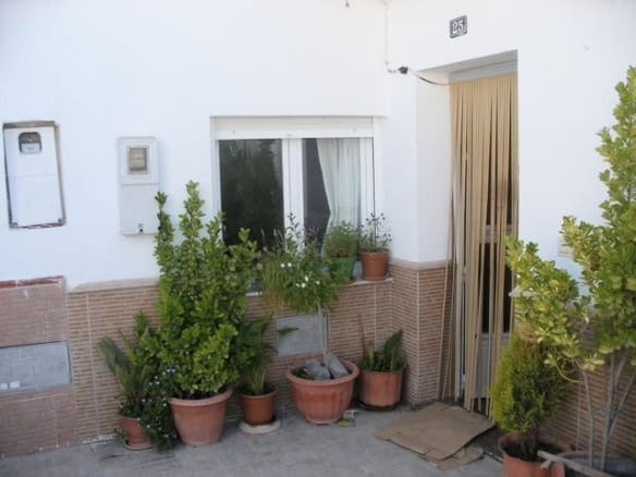 Cave house entrance with potted plants in Benamaurel, Granada, showcasing traditional rural architec.