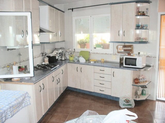 Charming cave house interior in Benamaurel, Granada, featuring a modern kitchen with white cabinets.