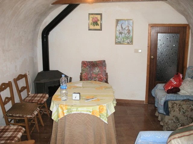 Cave house interior with cozy dining area, wooden chairs, and decorative wall art in Benamaurel, Gra.