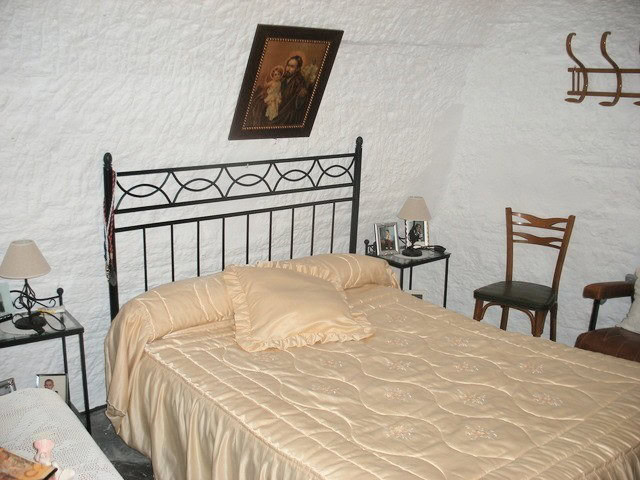 Cave house interior in Benamaurel, Granada, featuring a cozy bedroom with vintage furniture and trad.