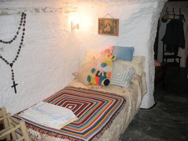 Charming cave house bedroom with colorful pillows and a rainbow blanket in Benamaurel, Granada. Uniq.