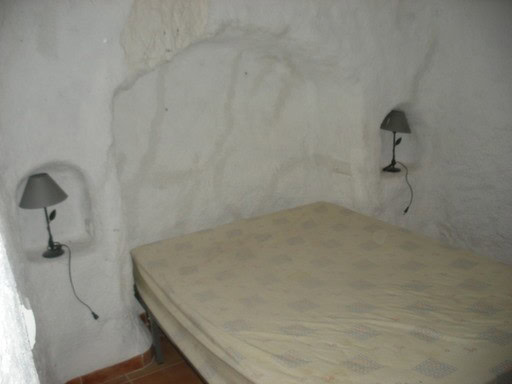 Cozy bedroom in a traditional village property in Gorafe, Granada with unique cave-style walls.