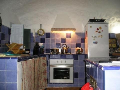 Cozy cave house kitchen with traditional blue tiles and modern appliances in Cortes de Baza, Granada.