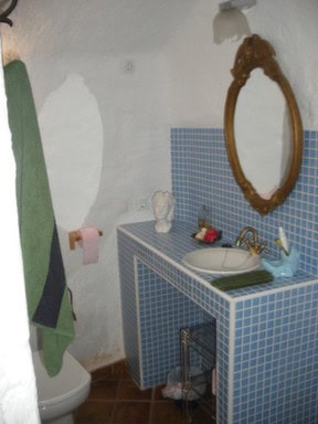 Cozy cave house bathroom with rustic mirror and blue tiled sink in Cortes de Baza, Granada.