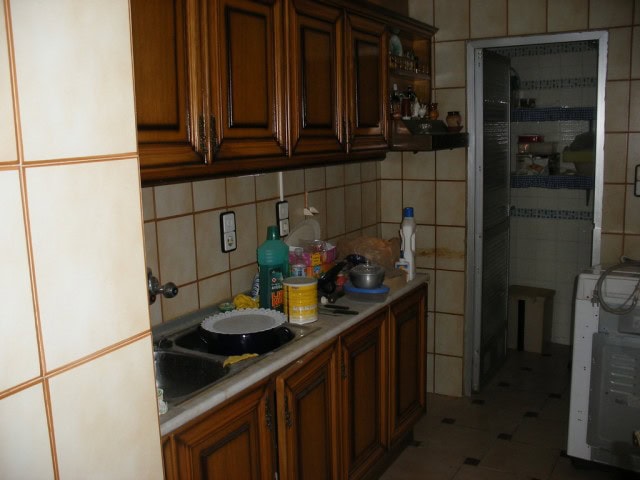 Traditional kitchen with wooden cabinets and tiled walls in Guadix village property.