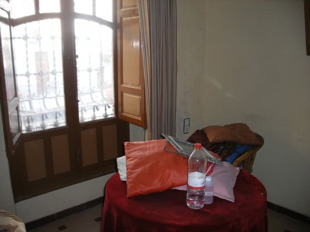 Cozy interior view of a village home in Guadix, Granada, featuring a small table with pillows, water.