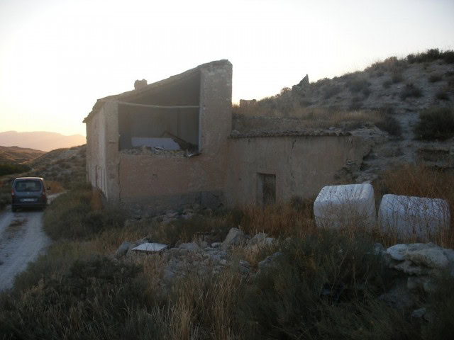 Abandoned rural building in Venta del Peral, Granada, with scenic mountain views and rustic charm.