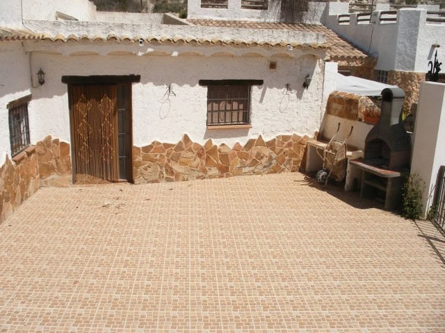 Cave house exterior with stone accents and outdoor seating in Cuevas del Campo, Granada.