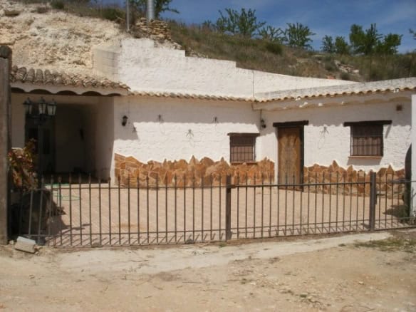 Cave house in Cuevas del Campo, Granada, with whitewashed walls and rustic wooden door.