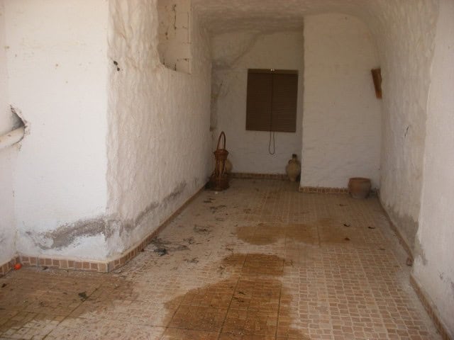 Interior view of a rustic cave house in Cuevas del Campo, Granada, showcasing whitewashed walls and.