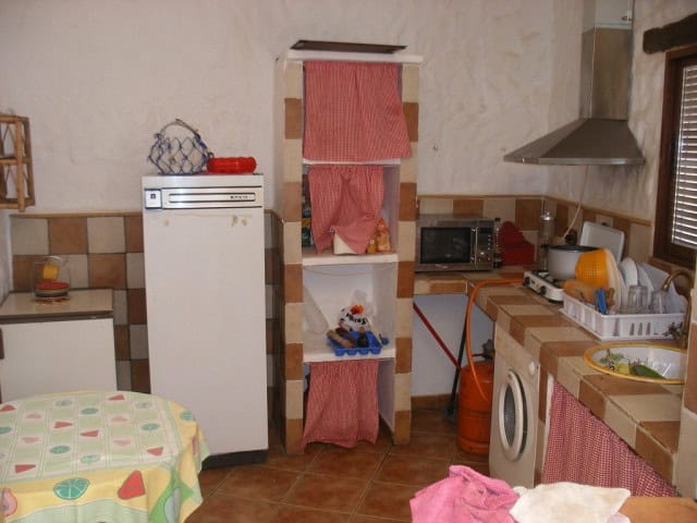 Cozy cave house interior with rustic kitchen and traditional decor in Cuevas del Campo, Granada.