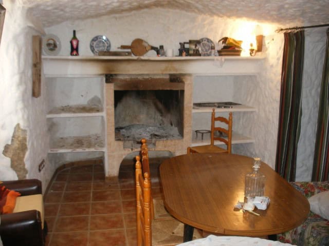 Charming cave house interior with rustic fireplace and traditional decor in Cuevas del Campo, Granad.