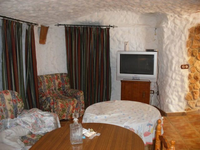 Traditional cave house living room with colorful curtains and vintage furniture in Granada.