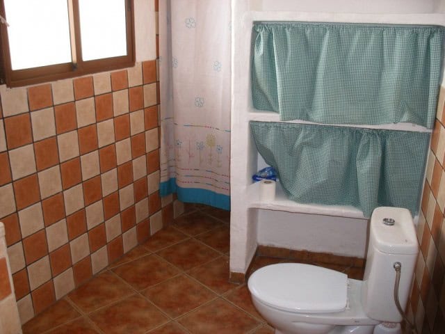 Interior view of a rustic cave house bathroom in Cuevas del Campo, Granada, with tiled walls and sim.