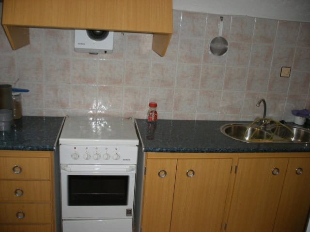 Cozy kitchen with wooden cabinets, sink, and stove in a cave house located in Castillejar, Granada.