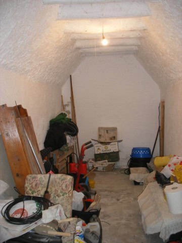 Cave house interior in Castillejar, Granada, showcasing rustic stone walls and storage space.