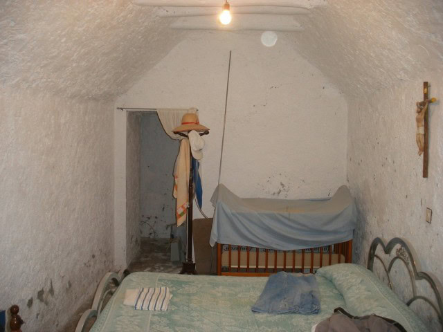 Cave house interior with rustic furnishings in Castillejar, Granada, featuring a cozy bedroom and tr.