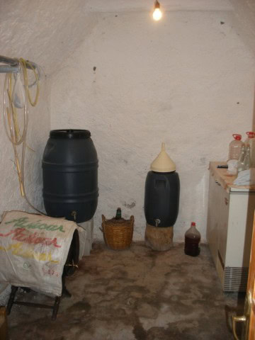 Cave house interior with water barrels, storage, and rustic decor in Castillejar, Granada. Unique un.