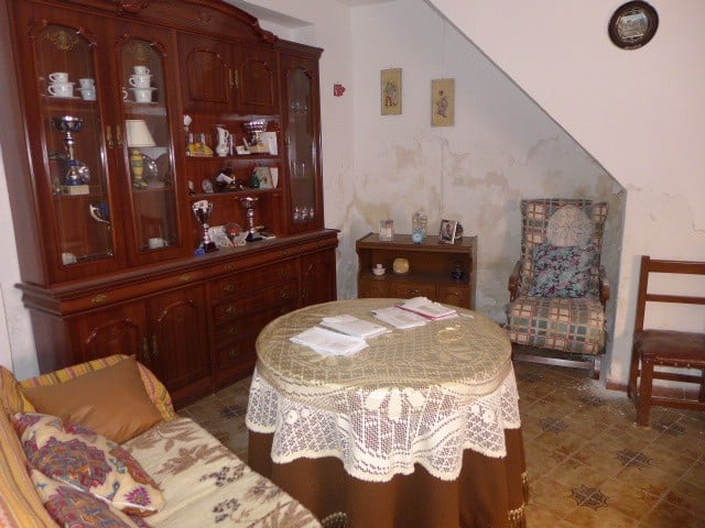 Spacious living room with vintage furniture and a lace-covered table in a traditional village home.