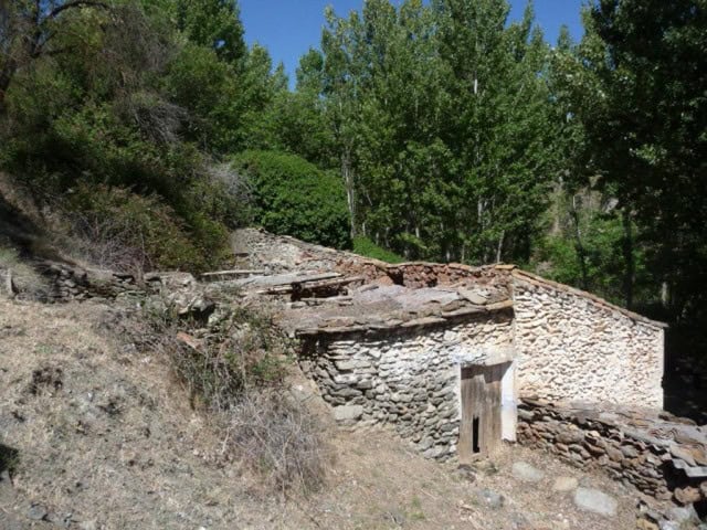Farm property in Baza, Granada with stone walls and lush greenery.