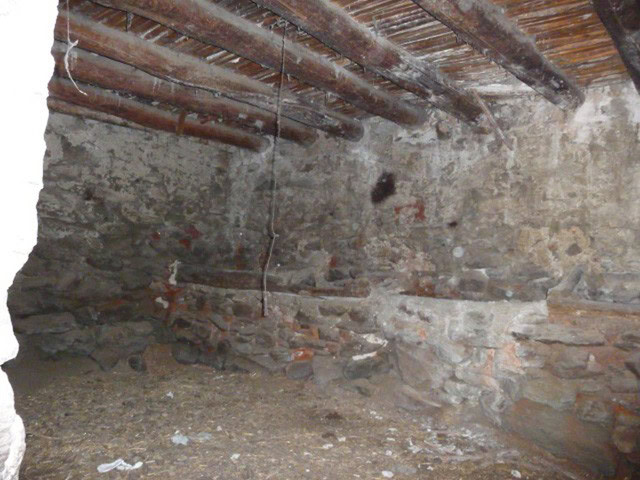 Farm property interior with rustic stone walls and wooden ceiling beams in Baza, Granada.