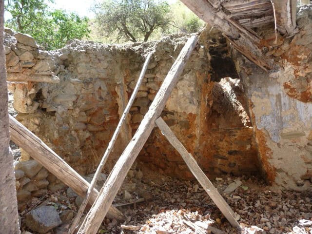 Farm property ruins in Baza, Granada, showcasing an abandoned stone structure with wooden beams and.