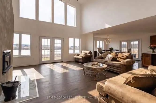 Bright living room with large windows overlooking a lake in Belmont, Ontario. Modern furniture and h.