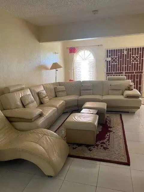 Spacious living area featuring a large beige leather sectional sofa and a cozy rug.