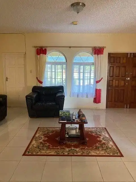 Spacious living room featuring large windows, comfortable black armchair, and decorative rug.