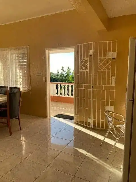Spacious interior with access to balcony overlooking lush greenery in Portland, Jamaica.