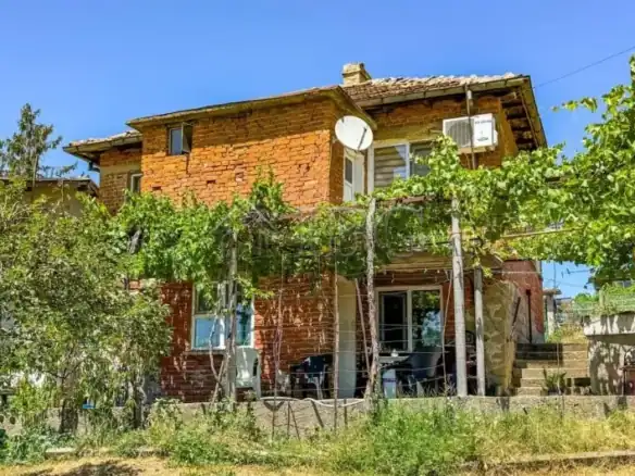 Two-story brick house with land in Sredets, Burgas, Bulgaria, featuring a garden and outdoor seating.