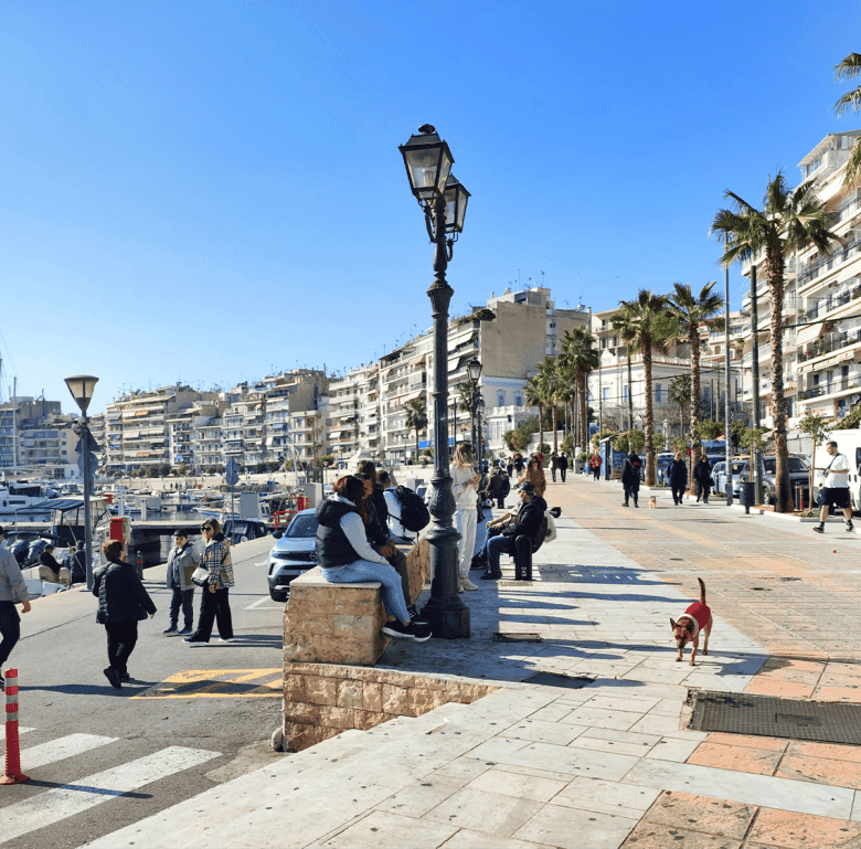 Athens waterfront promenade with palm trees, benches, and people enjoying the sunny day.