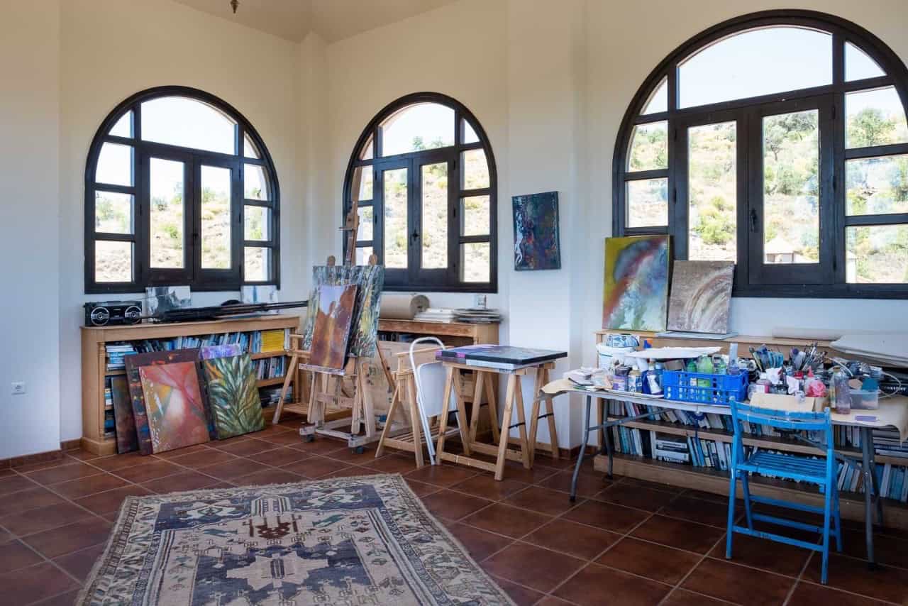 Bright art studio featuring large arched windows, easels, and painting supplies for creative work.