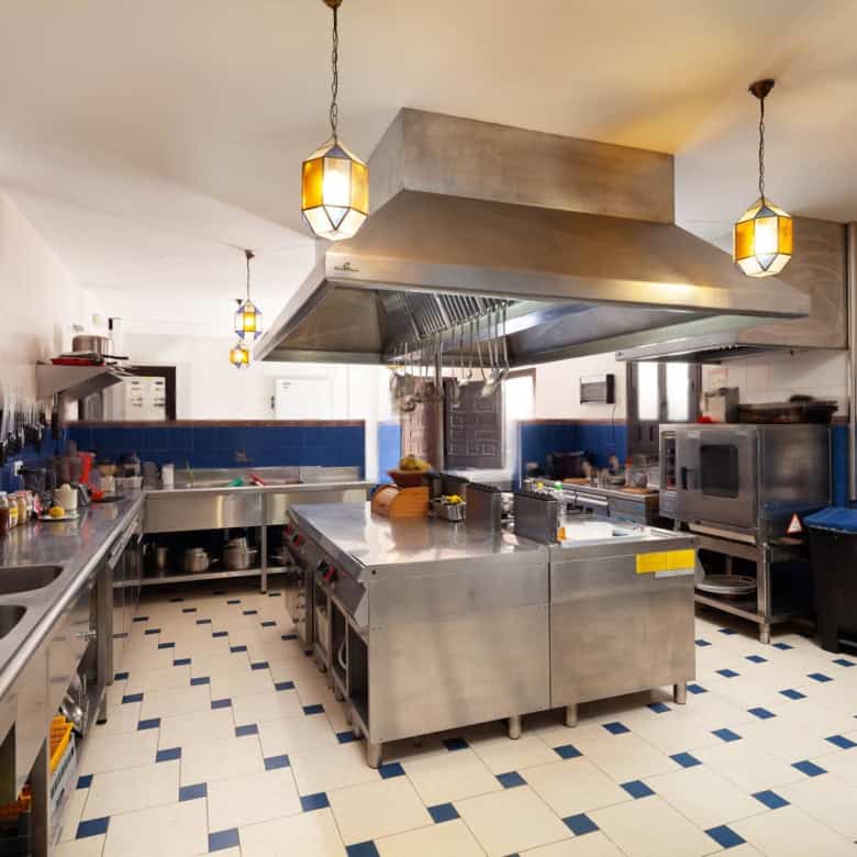 Commercial kitchen with stainless steel appliances and blue tiled walls.