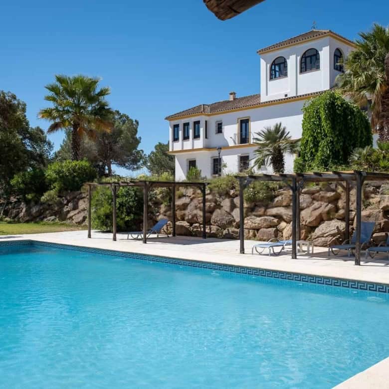 Beautiful villa with swimming pool, palm trees, and outdoor lounging area.