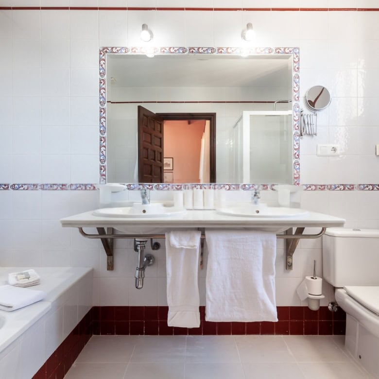 Bathroom with white tiled walls, large mirror, and modern fixtures.