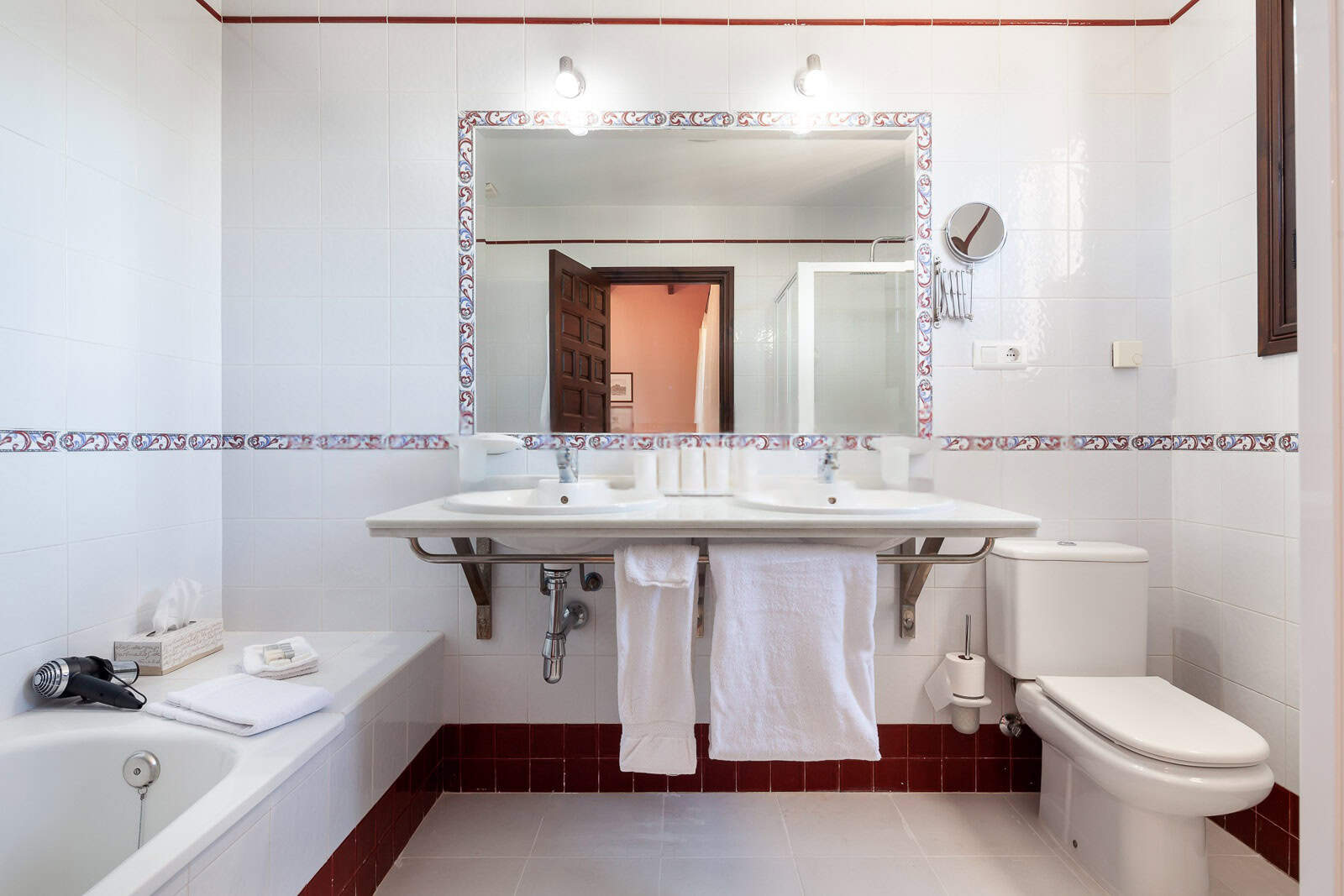Bathroom with white tiled walls, large mirror, and modern fixtures.