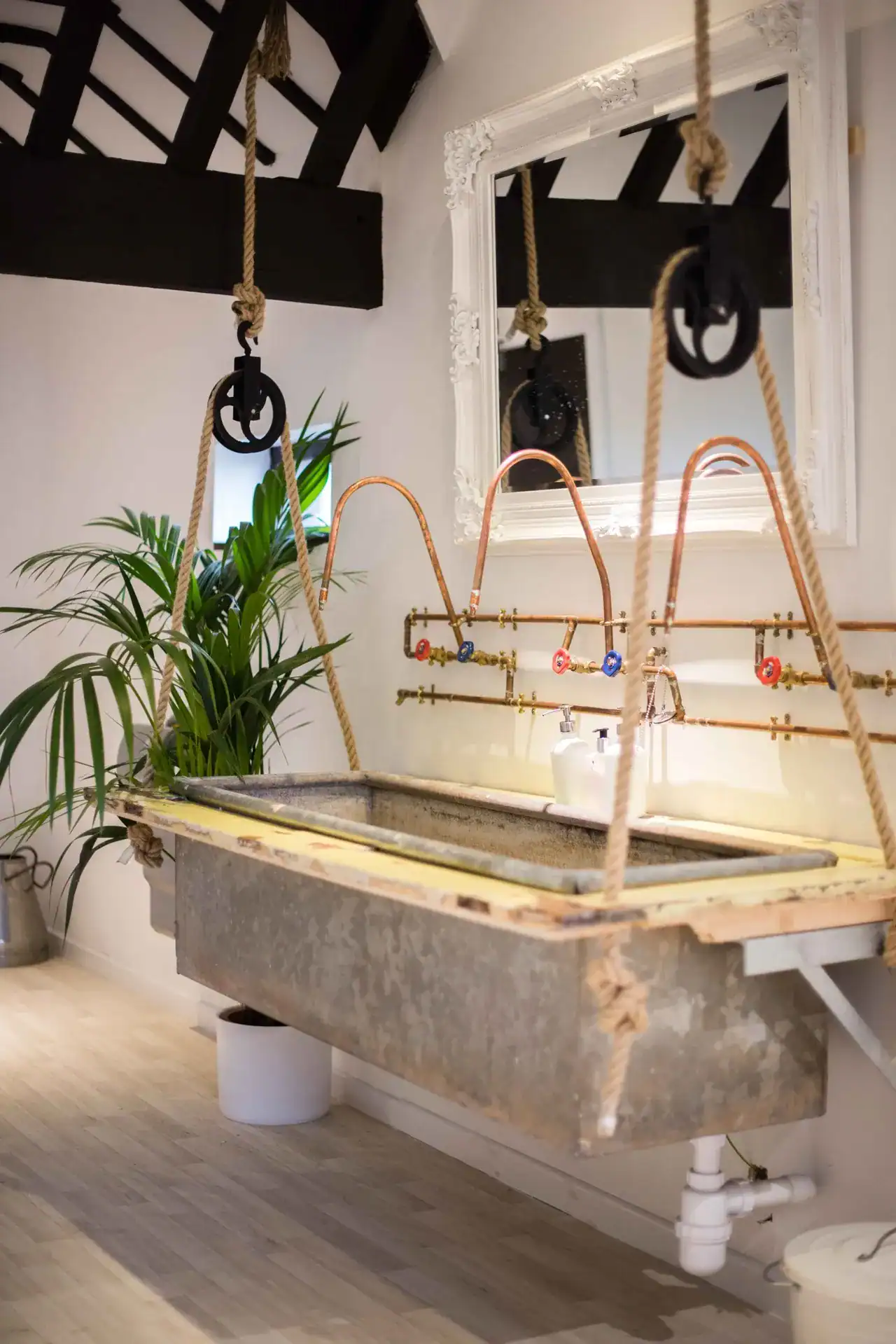 Vintage industrial-style laundry sink with copper pipes and hanging ropes, in a modern interior. Vintage industrial laundry sink with copper pipes and hanging ropes in a stylish home.