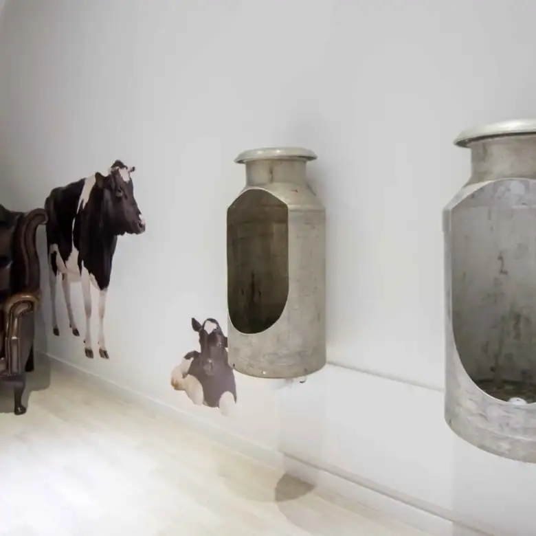 Decorative cow wall stickers and antique milk cans in a modern interior setting.
