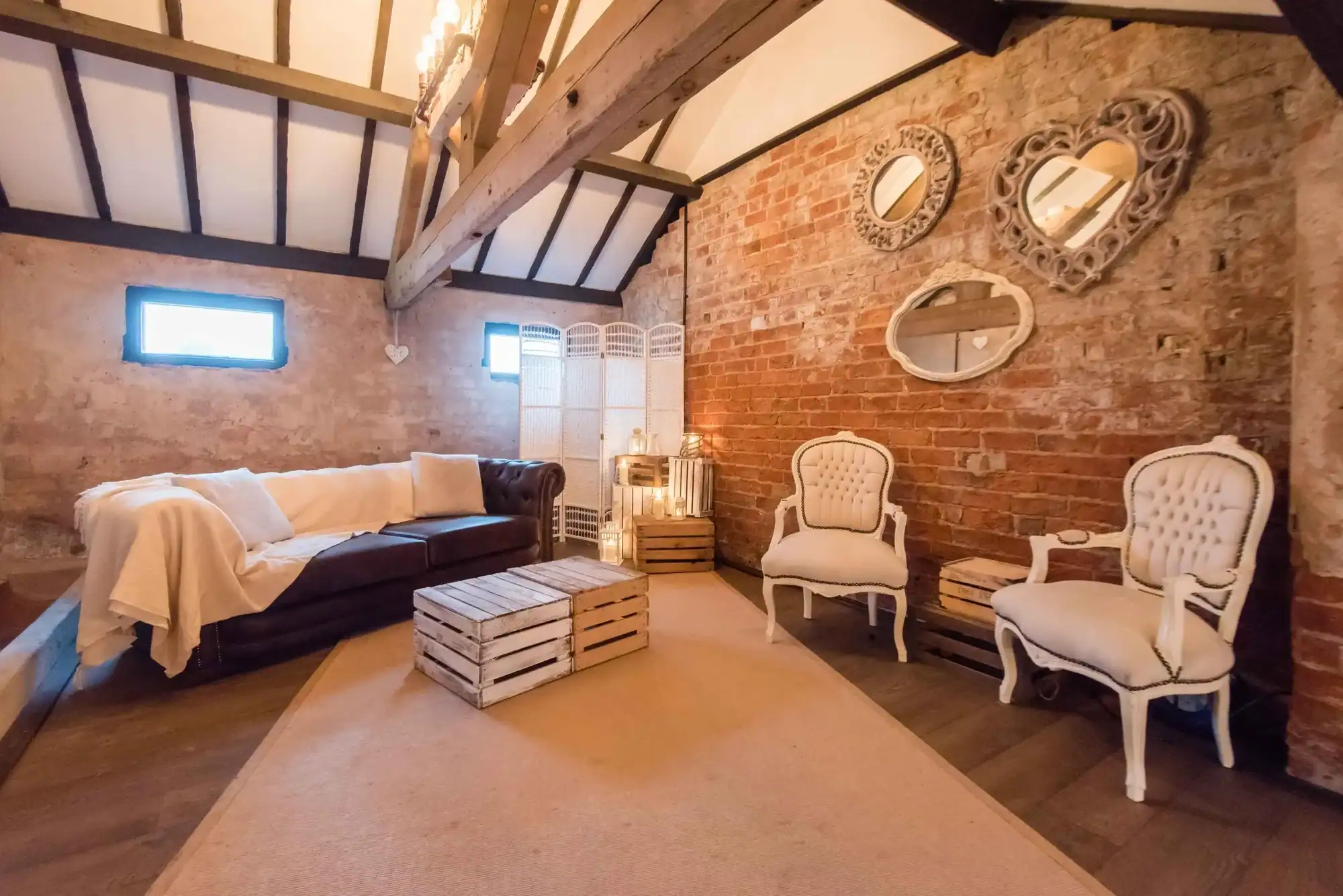 Charming rustic living room with exposed brick walls and vintage furniture Cozy living room featuring exposed brick walls, vintage armchairs, and decorative mirrors for a rust.