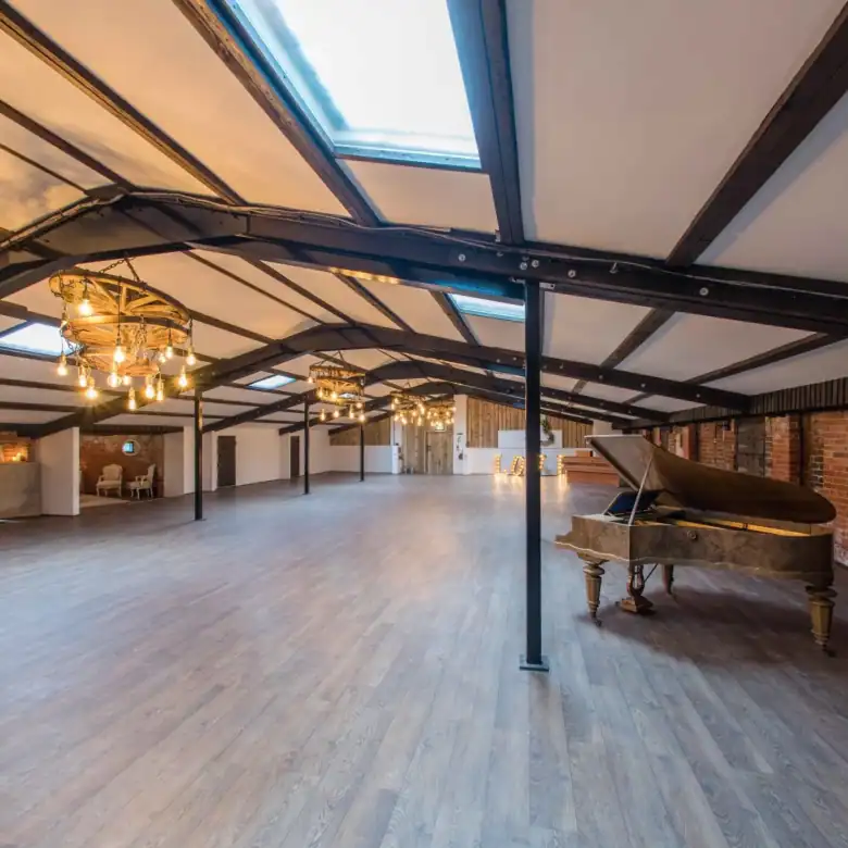 Interior view of a large loft featuring wooden floors, brick walls, skylights, and elegant chandelie.