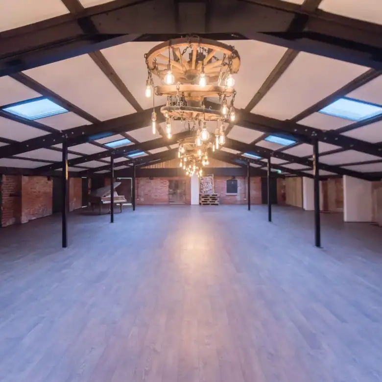 Large open-plan loft with brick walls, wooden flooring, and vintage chandeliers.
