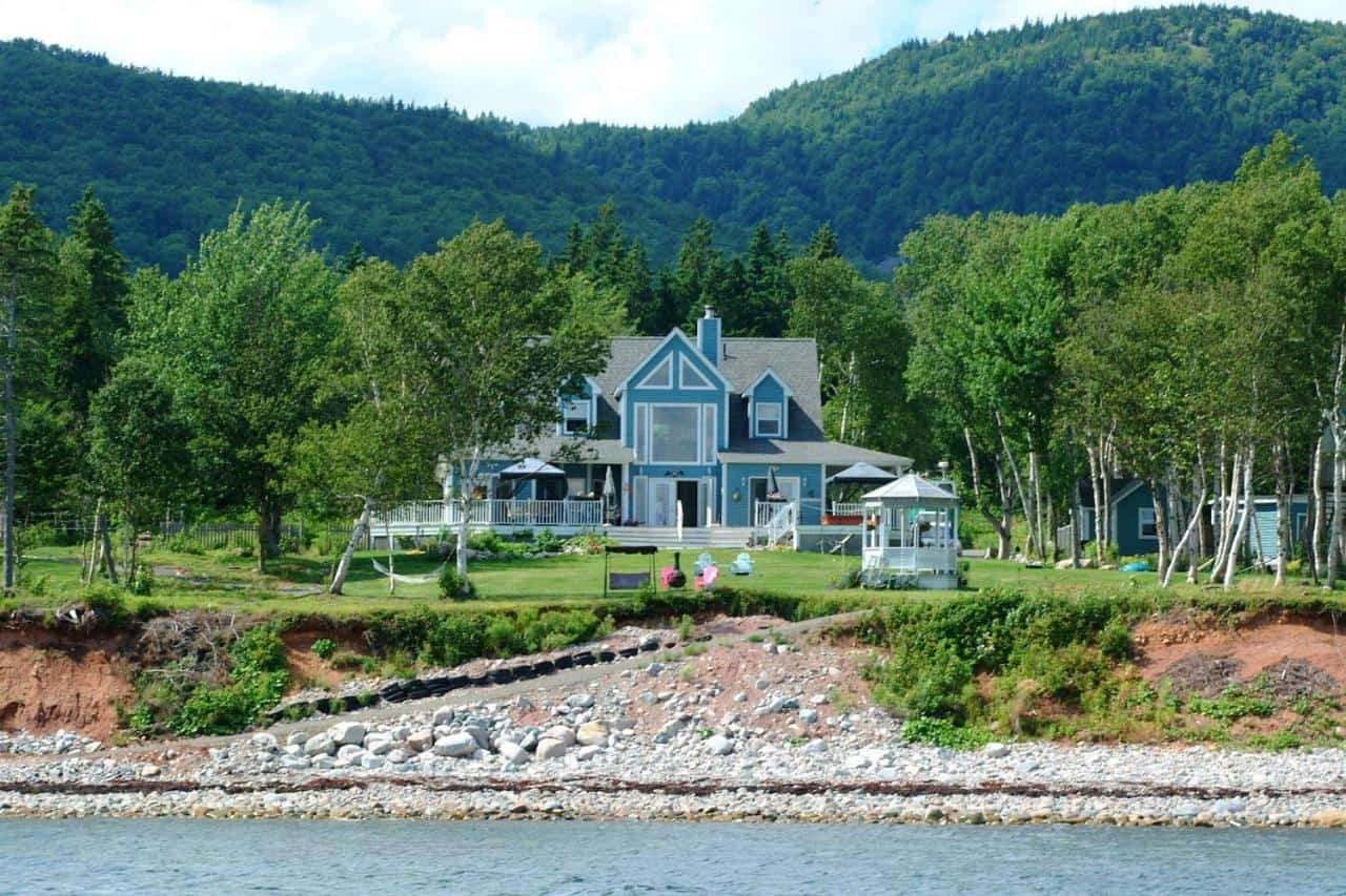 Ocean view manor for sale in Englishtown, Nova Scotia, with stunning waterfront and lush green surro.