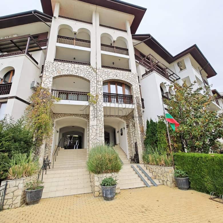 Bright exterior of a modern apartment complex with multiple balconies and stone accents, located nea.